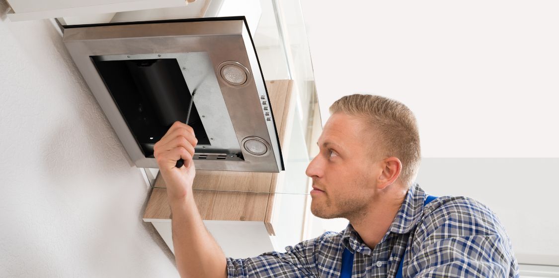 A Worker Replaces a Kitchen Range Hood