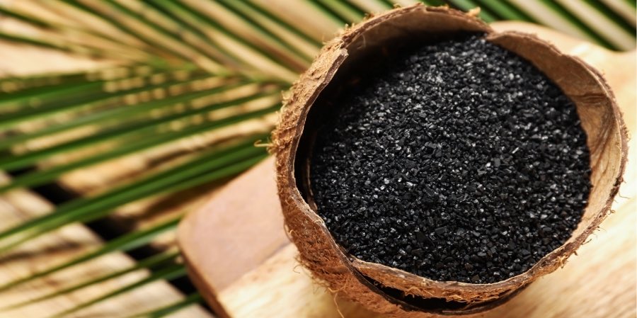 Powder and granules of activated carbon inside a coconut, showcasing its origin.